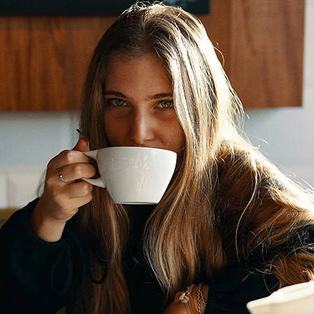 Woman sipping coffee in the morning at her kitchen table