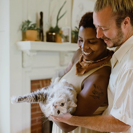 interracial couple holding their pet cat in their home