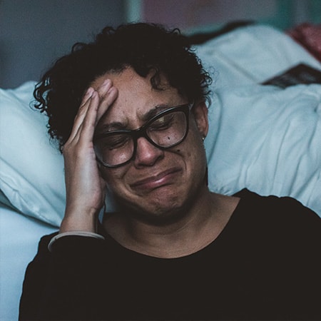 Woman crying next to her bed